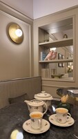 Un comedor con una mesa de mármol, tazas de té con estampado floral, un azucarero y una cafetera.