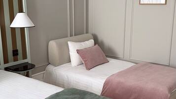 A hotel room with two beds, a nightstand, a lamp, and a framed picture on the wall.