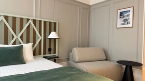 A hotel room with a bed, a chair, a nightstand, a lamp, and a framed picture on the wall. - Boutique Hôtel Le Clos Huguerie – Bordeaux Centre (Bordeaux)