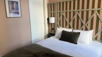 A hotel room with a bed, a nightstand, a lamp, and a framed picture on the wall.
