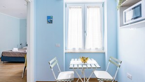 A room with a bed, a table with chairs, a window with blinds, and a wall-mounted TV. - Il Ciucciariello (Naples)