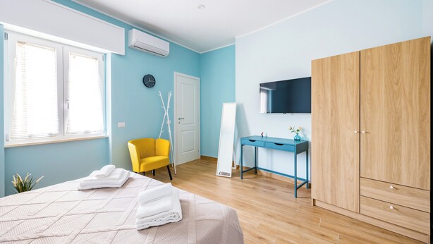 A bedroom with a bed, a desk, a wardrobe, and a chair. - Il Ciucciariello (Naples)