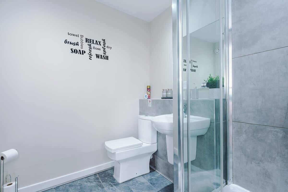 Een moderne badkamer met een douchecabine van glas, een toilet en een wastafel.