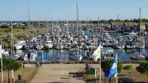 A marina with numerous boats docked, a cyclist on the path, and a flagpole with a flag.