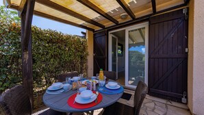 An outdoor patio with a round table set for dining, surrounded by wicker chairs.