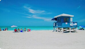 A lifeguard tower on a beach with clear blue water and a few people in the background. - "Venice Oasis: Beach-Ready Retreat!" (Venice)