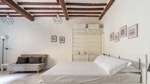 A bedroom with a bed, a sofa, a wardrobe, and framed pictures on the wall. - Pinzochere 16 N - Studio Apartment, Sleeps 2 (Firenze)
