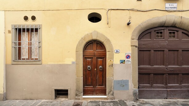 A building with a large wooden door, a window with bars, and a sign indicating a parking area. - Pinzochere 16 N - Studio Apartment, Sleeps 2 (Firenze)