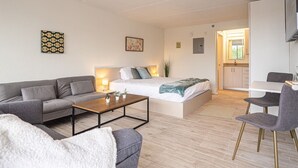 Una sala de estar moderna y bien iluminada con un sofá, una mesa de centro y una cama.