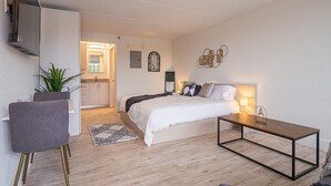 Une chambre à coucher moderne avec un lit, une table de chevet et un téléviseur fixé au mur.