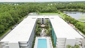 Un hôtel moderne doté d’une piscine centrale, entouré d’une végétation luxuriante et disposant d’un parking.