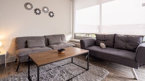 Una sala de estar moderna con dos sofás grises, una mesa de centro de madera y una alfombra gris.