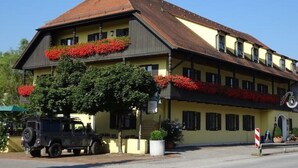 A traditional building with a sloped roof, multiple windows, and flower boxes on the upper floor. - Boardinghouse calf stretcher (Altdorf)