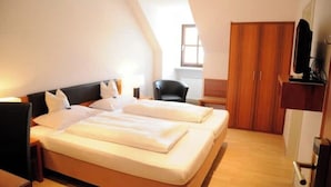 A hotel room with a large bed, a desk, a chair, and a wardrobe. - Boardinghouse calf stretcher (Altdorf)