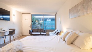 Une chambre d’hôtel moderne dotée d’un grand lit, d’un canapé, d’un bureau et d’un balcon offrant une vue sur la ville.