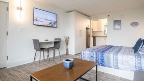 Habitació d'hotel amb un llit, escriptori, cadira, televisió i zona de cuina.