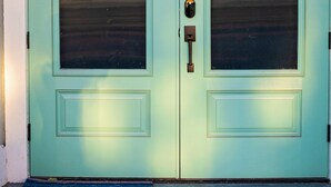 Una porta doppia color acquamarina con un piccolo tappetino davanti.