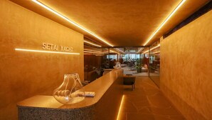 Un área de recepción con un mostrador de piedra, un florero de cristal y un letrero que dice "SETAI YACHT".