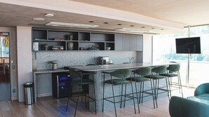 Una cocina moderna con encimera de granito, taburetes de bar y estanterías empotradas.