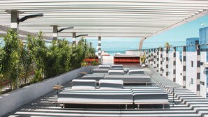 Una terraza en la azotea con filas de asientos, una piscina y vistas al océano.