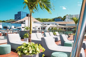A rooftop lounge area with lounge chairs, potted plants, and a view of buildings in the background. - Setai Yacht S3 - By Almare Flats (João Pessoa)