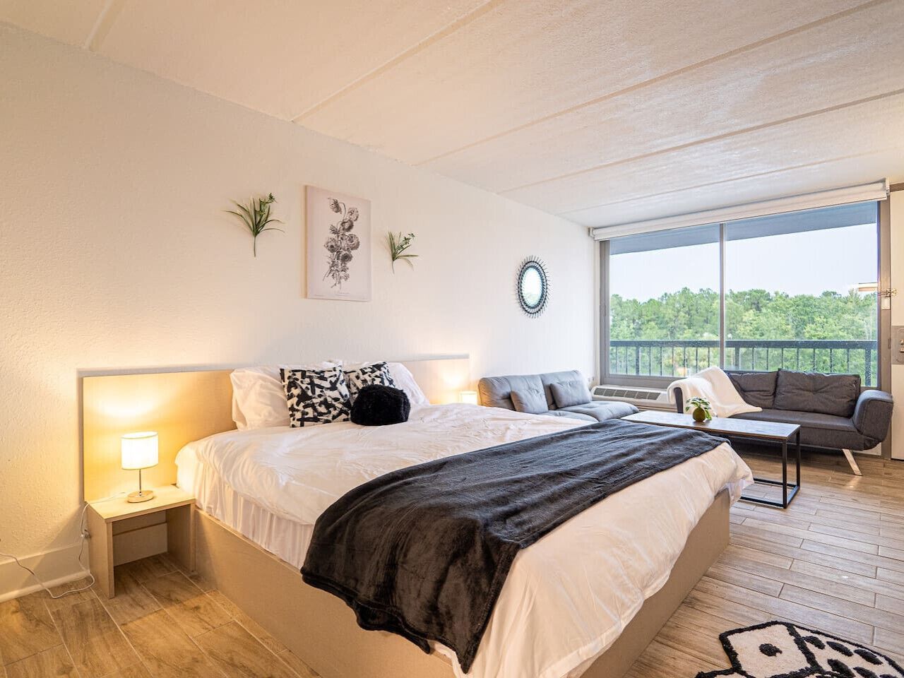 Une chambre avec un grand lit, des tables de chevet, un canapé et un balcon avec vue.