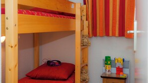 A bunk bed with a red pillow and a small table with toys. - travelski home classic - Résidence Les Balcons d'Anaïs 3* - 3 pièces 4/6 personnes (Villarodin-Bourget)