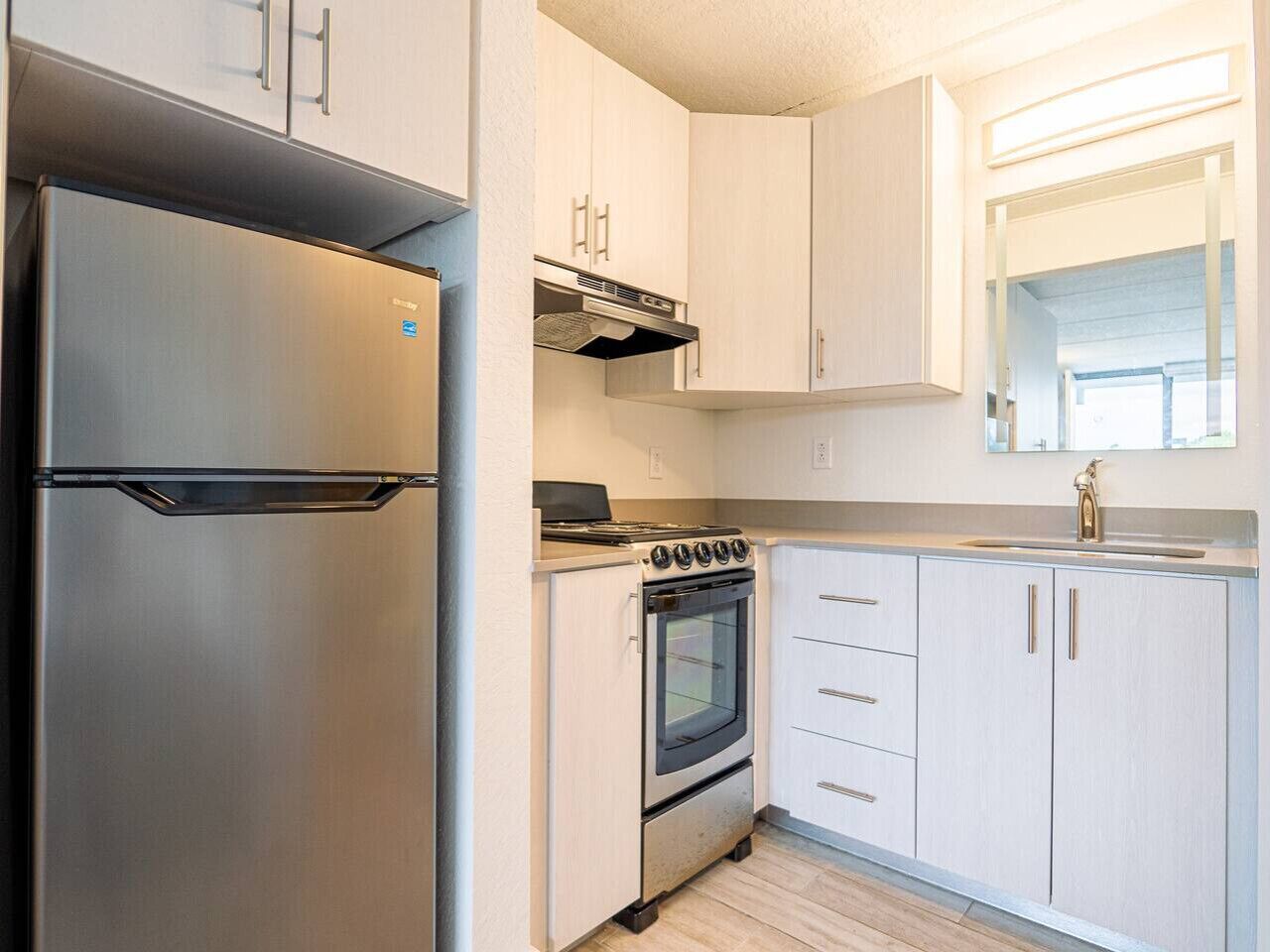 A modern kitchen with stainless steel appliances, white cabinetry, and a built-in oven.