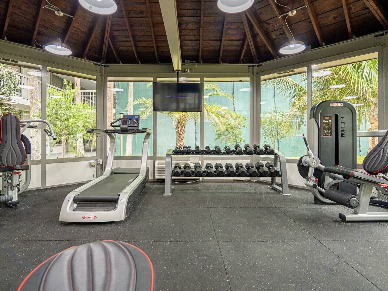 Un gimnasio con cintas de correr, mancuernas y máquinas de pesas.