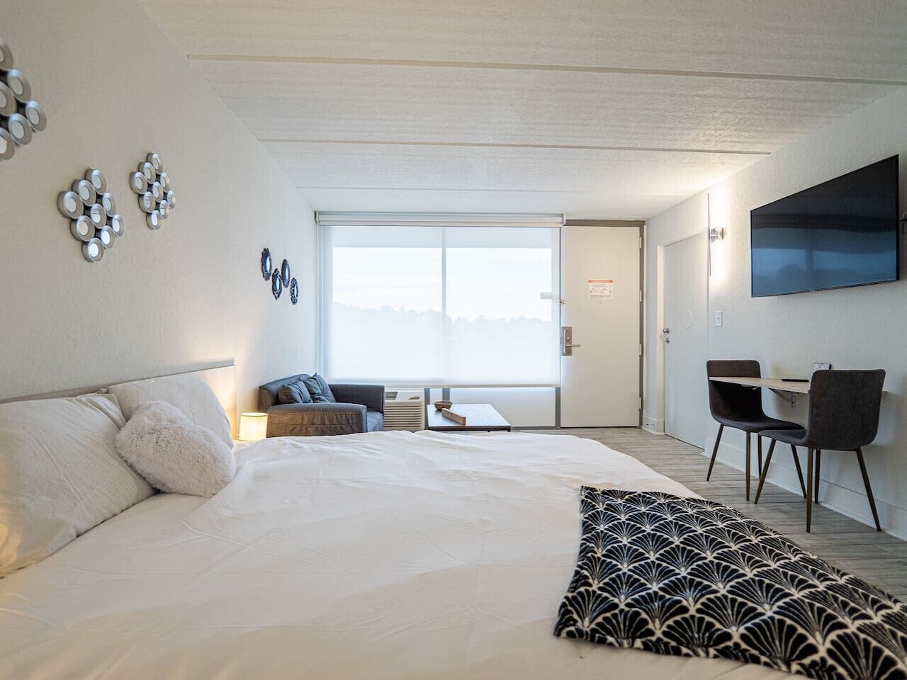 A modern hotel room with a large bed, a desk, and a TV.