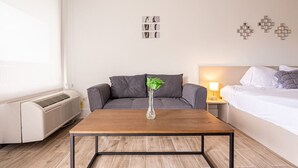 Ein modernes Hotelzimmer mit einem Holztisch, einem grauen Sofa und einem Bett mit weißen Bettwäsche.