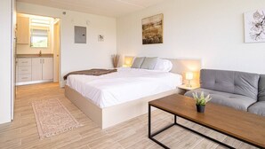 A bedroom with a bed, bedside table, lamp, and a grey sofa. - Stylish 1BR Escape in Kissimmee, minutes to Disney (Kissimmee)