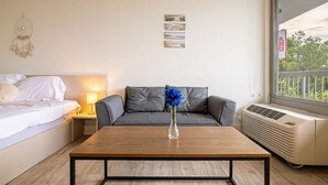 Een hotelkamer met een bed, een bank, een salontafel, een lamp, een kunstwerk aan de muur en een raam met uitzicht.