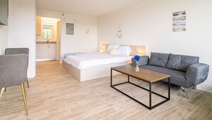 Een moderne slaapkamer met een bed, een grijze bank, een houten salontafel en een klein bureau.