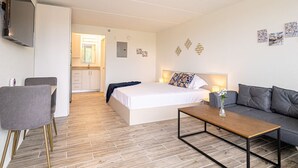 Ein modernes Hotelzimmer mit Bett, Sofa, Couchtisch und einem an der Wand montierten Fernseher.