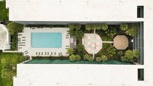 An aerial view of a hotel with a swimming pool, sun loungers, and a circular seating area surrounded by greenery. - Kissimmee 1BR Cottage W/Lake view & Next to Disney (Kissimmee)