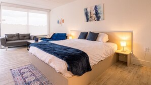Un dormitorio con una cama grande, mesitas de noche, un sofá y una ventana.