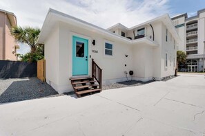 A modern two-story residential building with a turquoise door, a small set of wooden stairs, and a parking area in front. - Private beach studio apartment (Jacksonville beach)