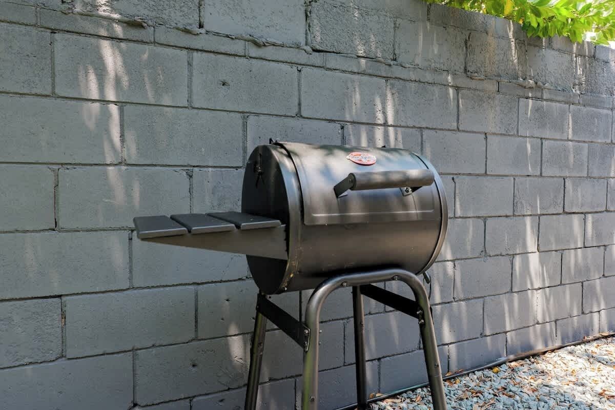 Ein tragbarer Gasgrill mit einer Seitablage vor einer Betonwand mit einem Metallgestell.