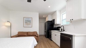 Ein gemütlicher Raum mit Bett, einer Küchenzeile und einem braunen Sofa.