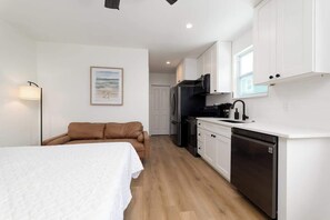 A compact room with a bed, a kitchenette, and a brown sofa. - Private beach studio apartment (Jacksonville beach)