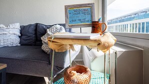 En mysig balkong med ett litet bord, en mugg och en välkomnande skylt för ett avkopplande boende vid havet.