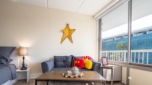 A modern living room with a sofa, a coffee table, and a star decoration on the wall. - Kissimmee 1BR Gateway W/pool view  Close to Disney (Kissimmee)