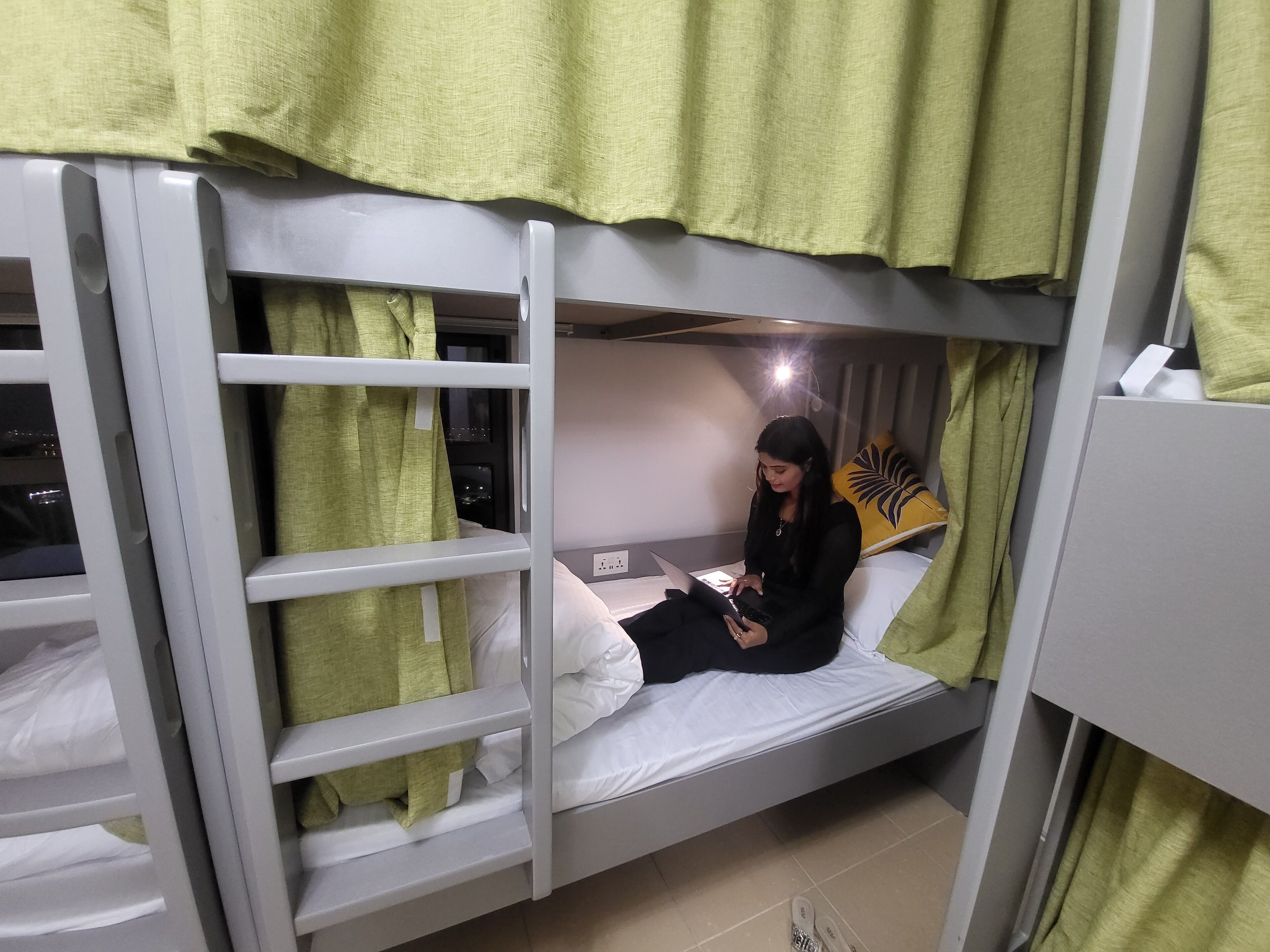 Habitación con literas y una persona usando una computadora portátil.