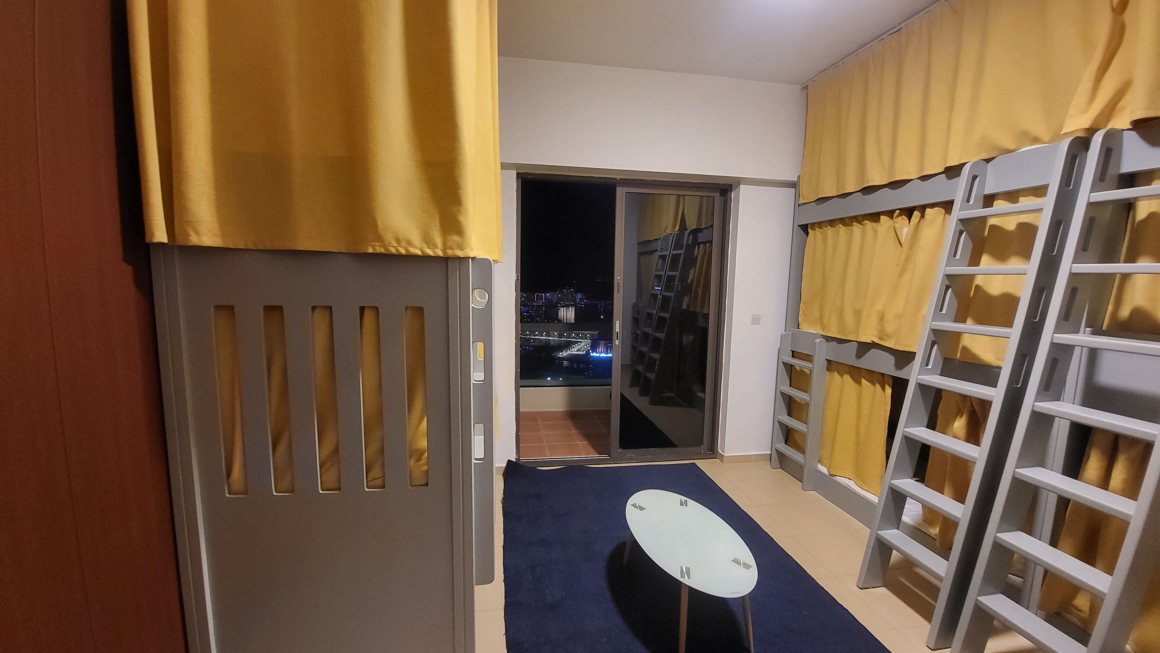 Una habitación con puerta corredera que da a un balcón con vista a la ciudad de noche.