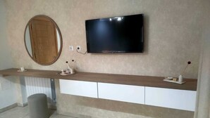 Un bagno moderno con un mobile bagno in legno, una TV a parete e uno specchio rotondo.