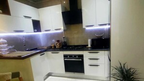 Una cucina moderna con mobili bianchi, un piano cottura nero e un ripiano con diversi oggetti.