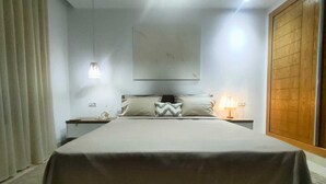 Camera da letto moderna con un letto grande, un comodino, una lampada e un'opera d'arte appesa al muro.