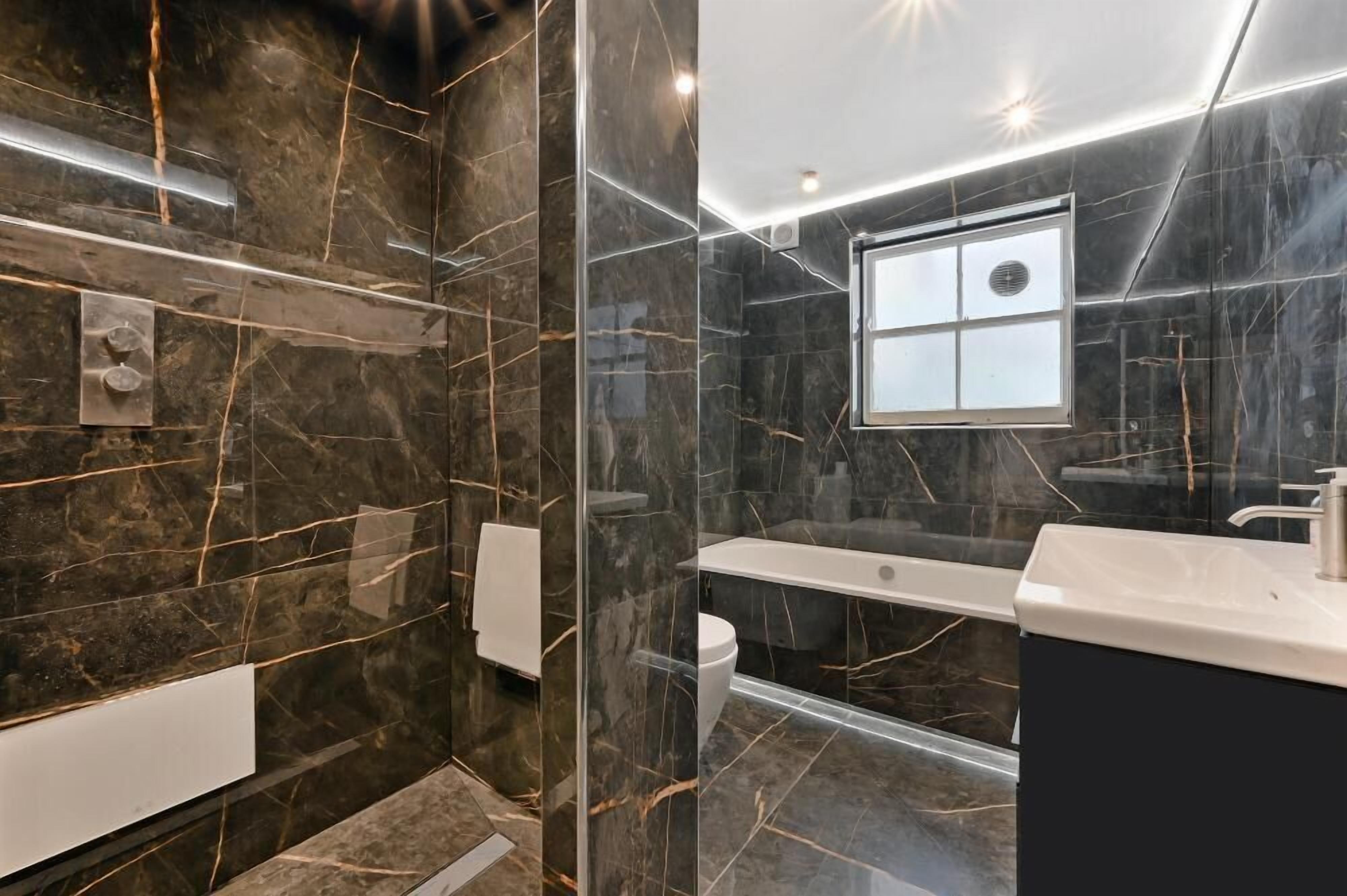A modern bathroom with a glass-enclosed shower, a bathtub, and a vanity with a mirror.