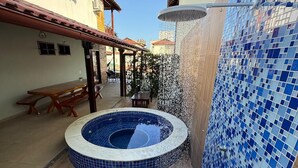 A swimming pool with a tiled edge, a covered seating area, and a wall with blue mosaic tiles. - Casa Carneiros 4QTS-JacuzziEChurrasq 039 (Tamandaré)